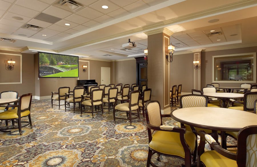 A well-appointed conference room with seating, a projector screen, and elegant carpeting.