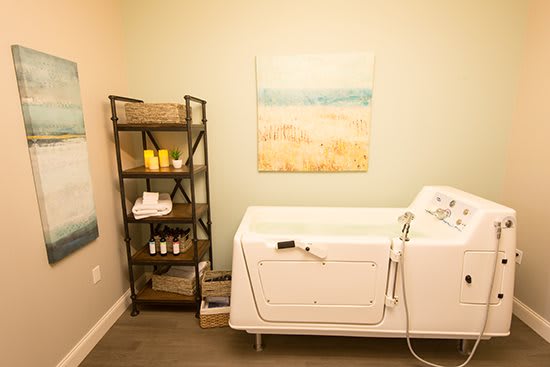 A serene spa room with a white bathtub and neatly arranged shelves, creating a relaxing atmosphere.