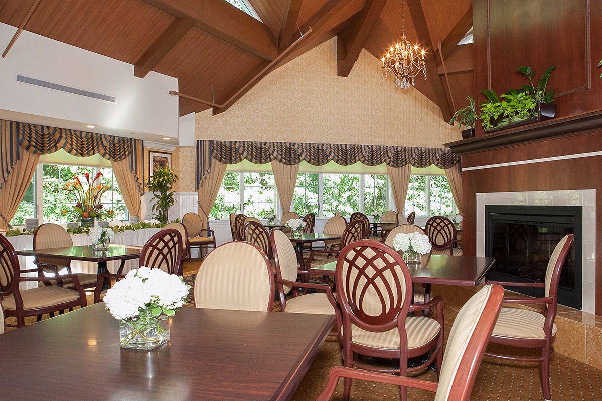 An elegant dining room with wooden tables, upholstered chairs, and a chandelier hanging from the ceiling.