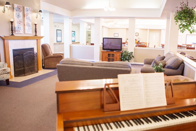 A cozy living room with a piano and television, featuring comfortable couches.