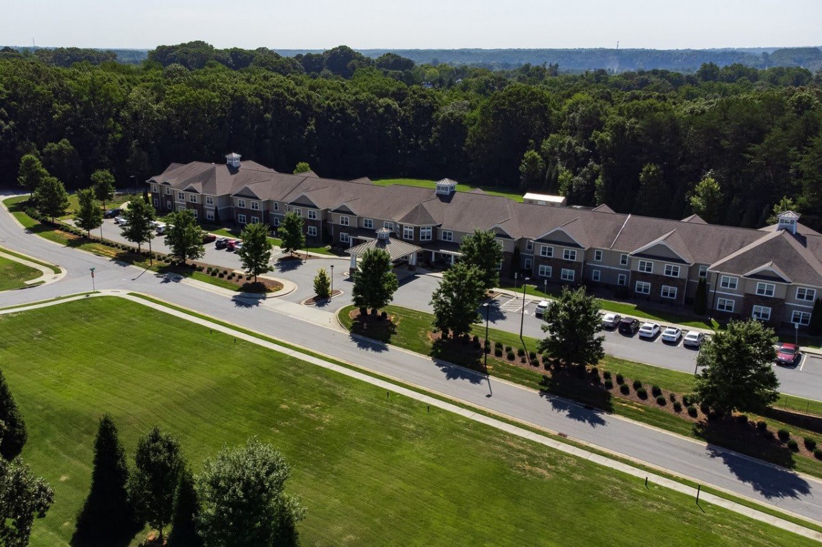 Aerial view of a residential complex with surrounding greenery and a parking lot.