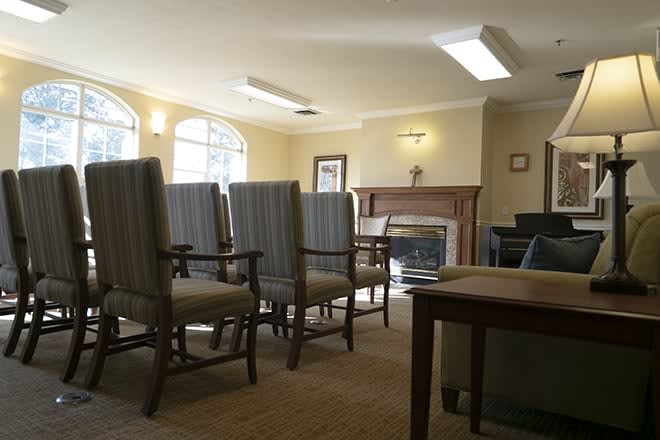 A well-lit meeting room with several chairs facing a fireplace.
