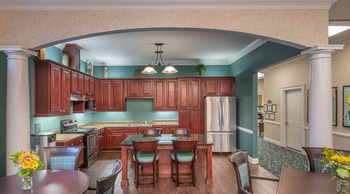 A modern kitchen with wooden cabinets and a central dining area.