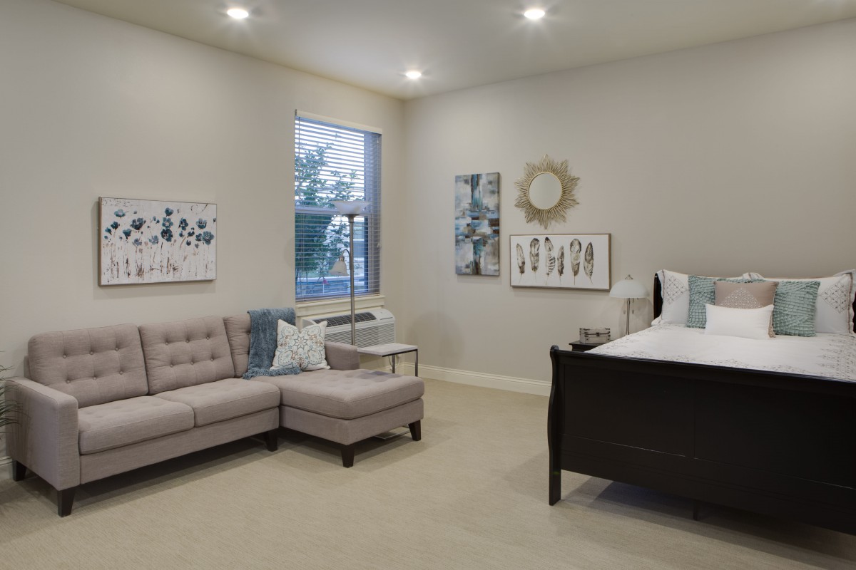 A modern living room with a neutral color scheme, featuring a sofa and contemporary artwork.