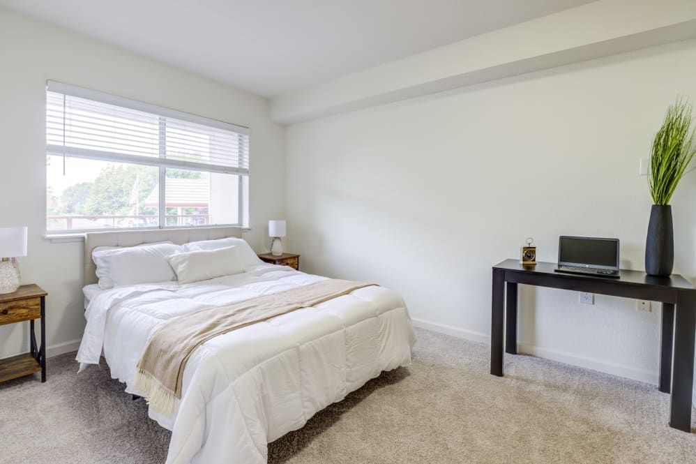 A minimalist bedroom with a cozy bed and a small desk.
