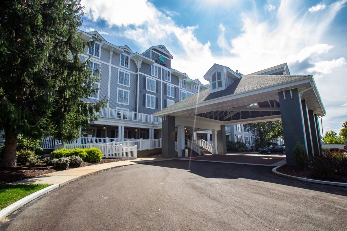 A hotel building with a driveway and entrance under a partly cloudy sky.
