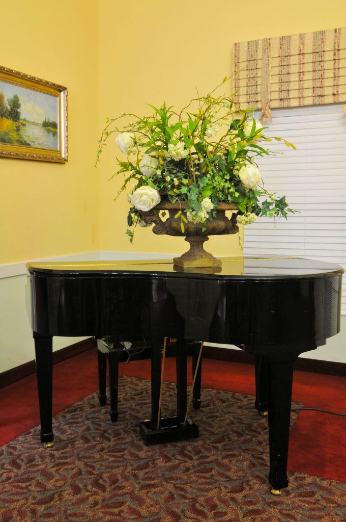 A grand piano adorned with a floral arrangement in a cozy room.