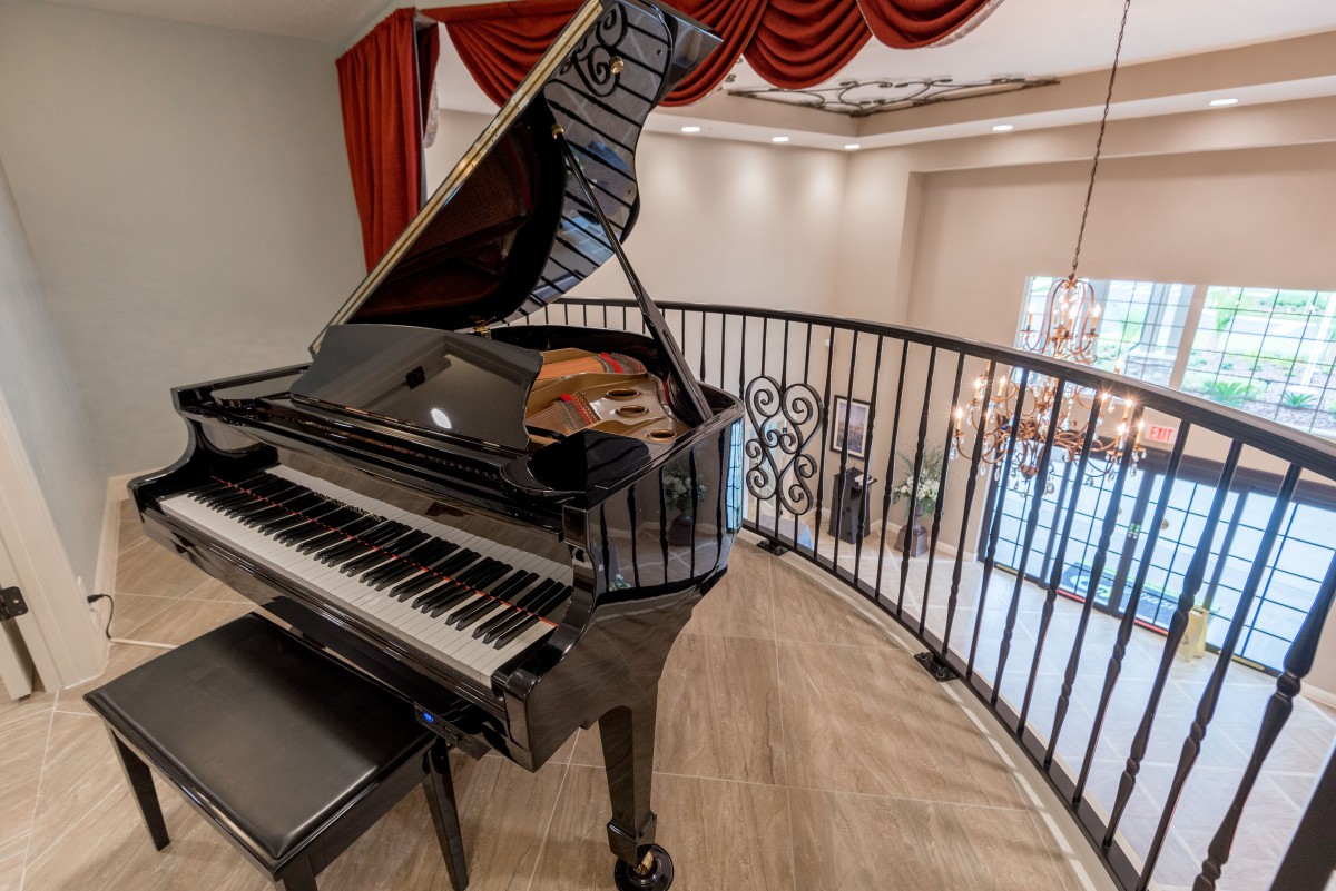 A grand piano elegantly placed on a balcony overlooking a stylish interior.
