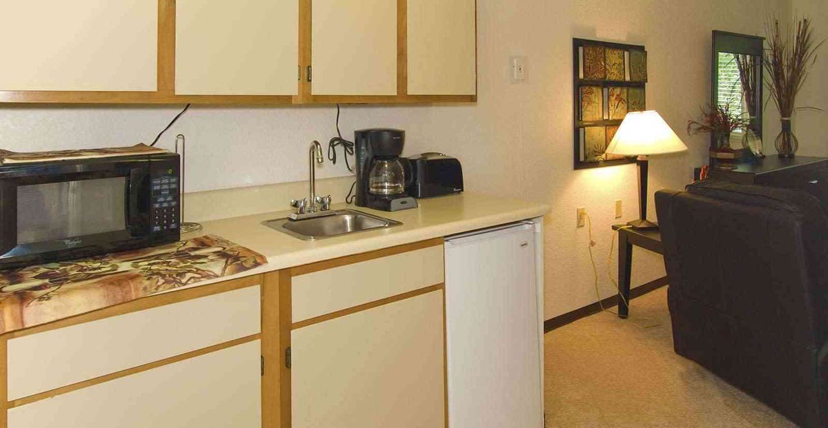 A small kitchen area featuring a coffee maker, sink, and microwave on the countertop.