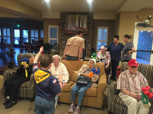 A warm community gathering where children and volunteers engage with elderly residents in a care facility.