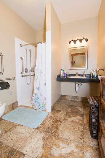 A spacious bathroom featuring a shower area, sink with mirror, and accessible amenities.