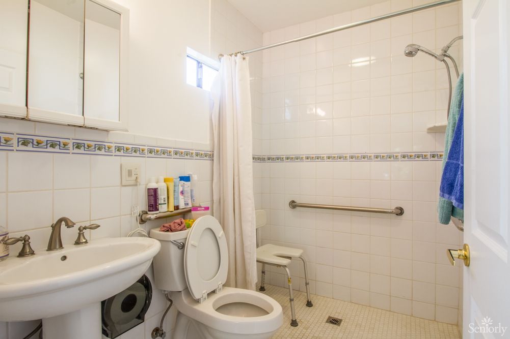 A clean and modestly decorated bathroom with a shower, toilet, and sink.