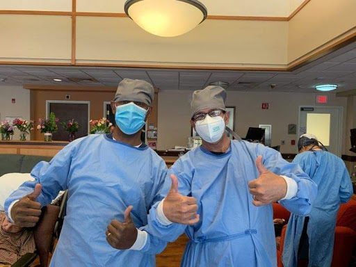 Healthcare workers celebrating teamwork with a thumbs-up gesture in surgical attire.