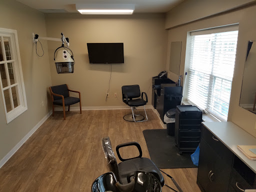 A minimalistic hair salon setup featuring a waiting area, a barber chair, and essential equipment for hair styling.