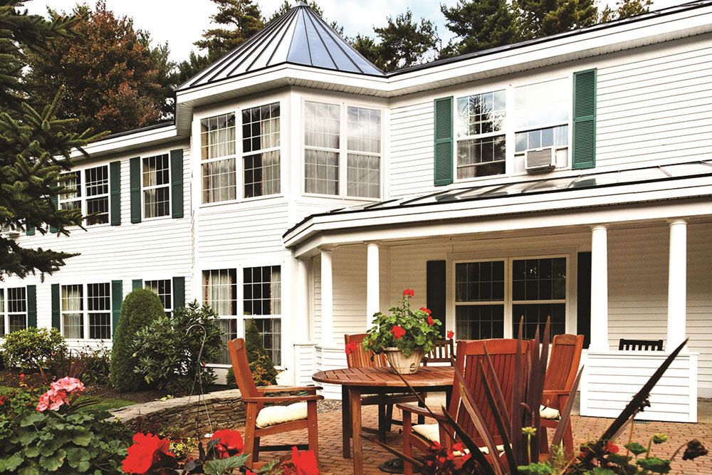 A beautiful house with a patio featuring outdoor furniture and potted plants.