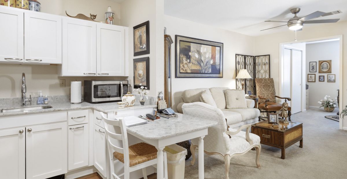 A cozy open-concept kitchen and living room with a white color scheme and elegant decor.