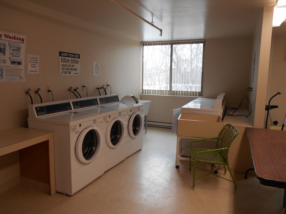 A laundry room with washing machines and dryers near a window.