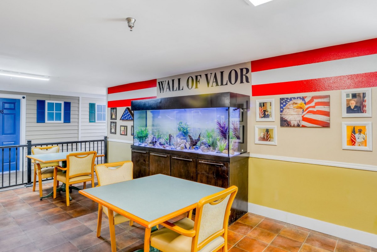 A cozy interior space featuring an aquarium under a 'Wall of Valor' theme with patriotic decorations and seating.