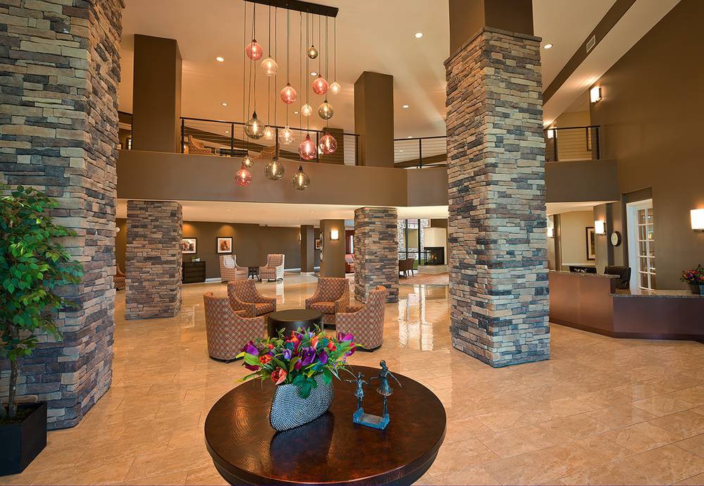 A modern lobby with elegant lighting, stone columns, and comfortable seating.