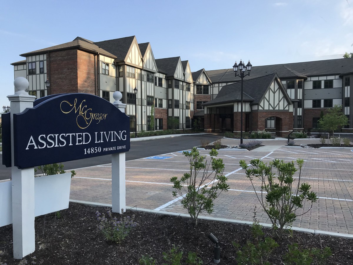 A three-story assisted living facility with a welcoming entrance and neatly landscaped surroundings.