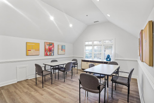 A modern, well-lit meeting room featuring tables and chairs, adorned with colorful artwork on the walls.