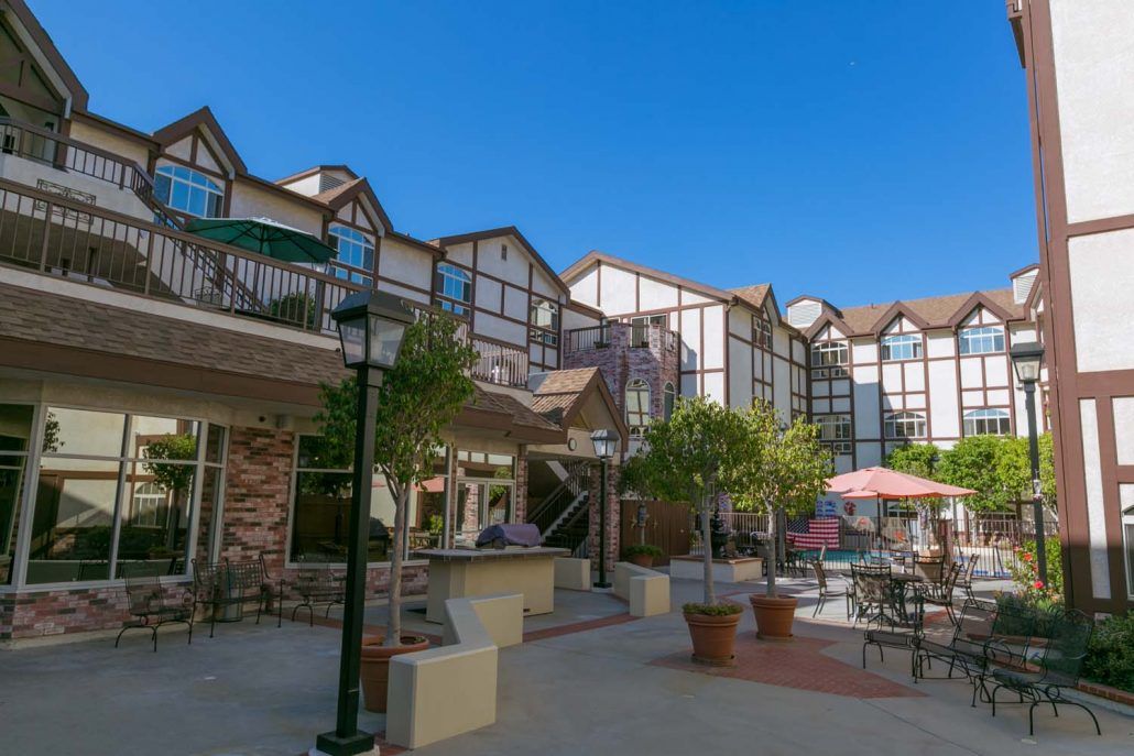 A courtyard with seating and umbrellas in front of a multi-story building.