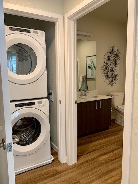 A modern home laundry area with a stacked washer and dryer, adjacent to a bathroom with contemporary decor.