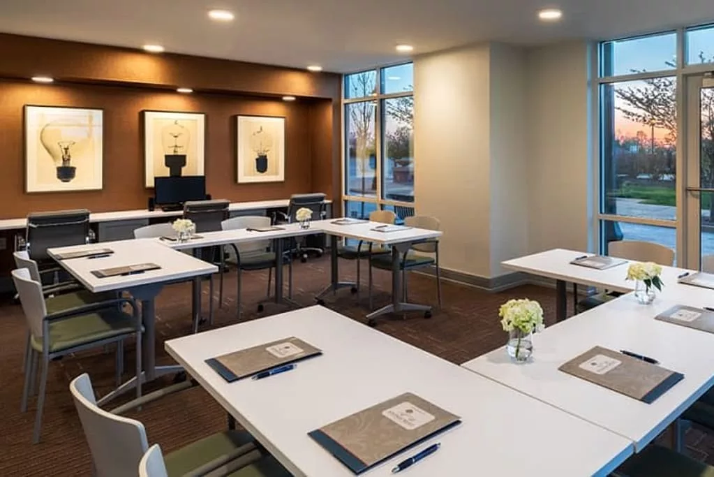 A modern conference room set up with tables, chairs, and notepads ready for a meeting.