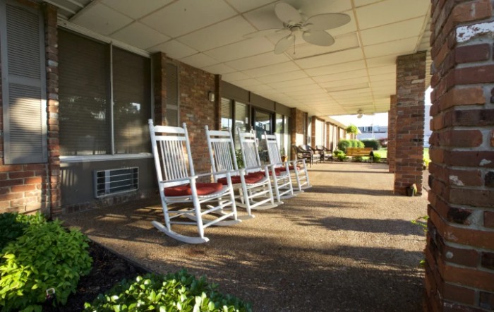 A row of rocking chairs on a sunny porch, inviting relaxation.