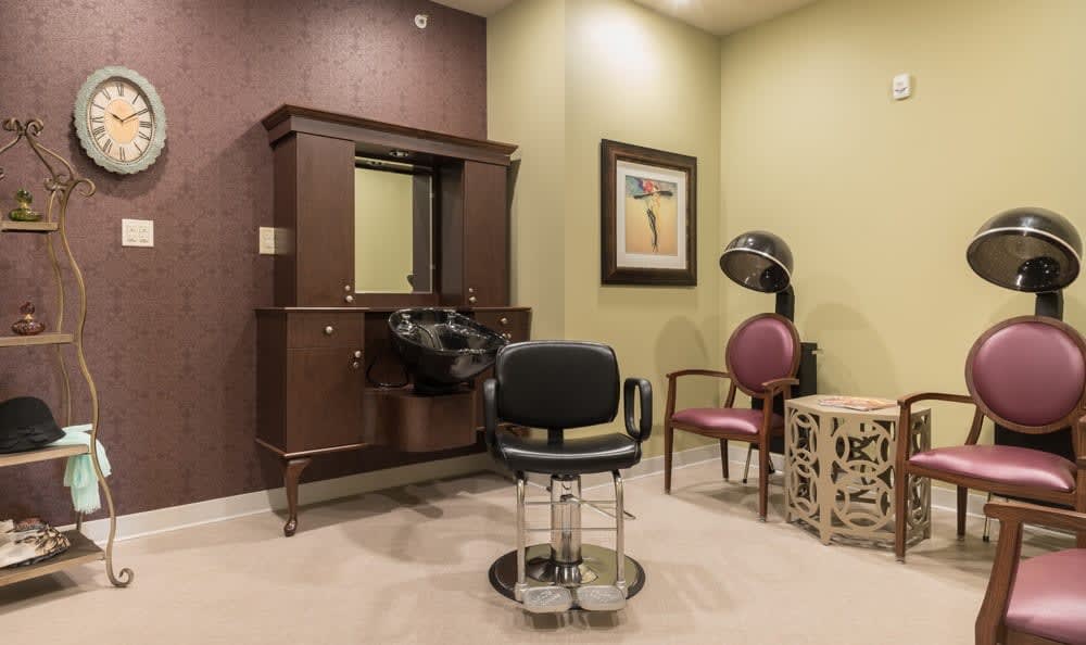 An interior view of a hair salon featuring a salon chair, mirror, and hair dryer.