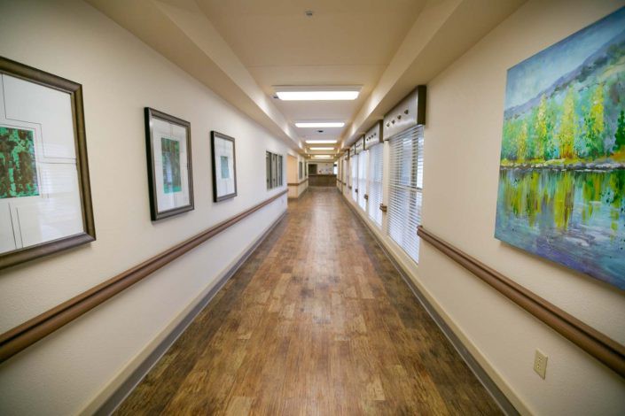 A long, well-lit hallway with framed artwork on the walls.