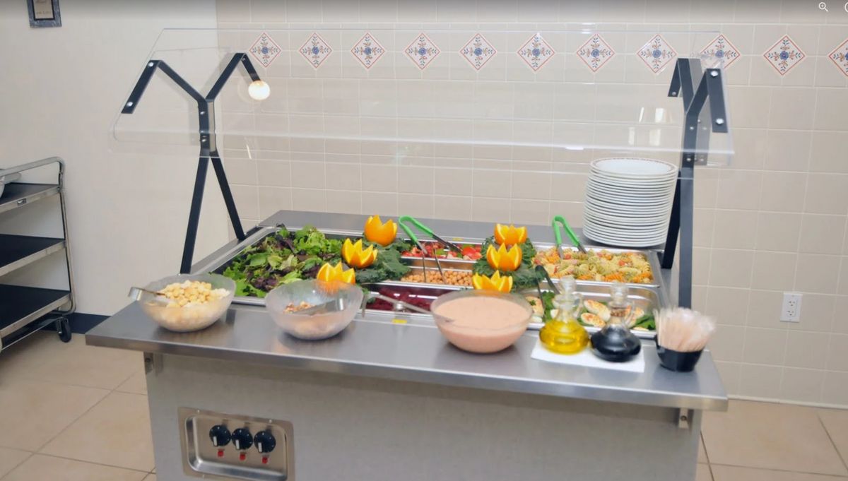 A buffet table with a variety of salads and vegetables arranged for self-service dining.
