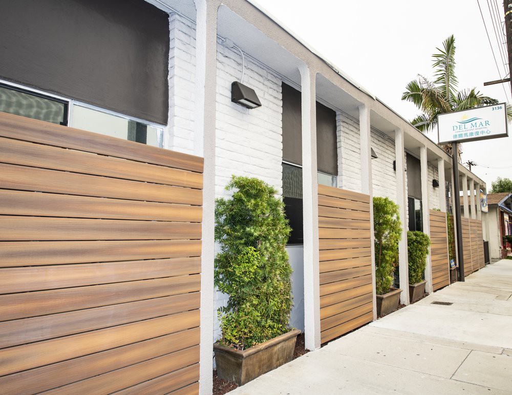 A modern building exterior featuring sleek wooden paneling and potted greenery.