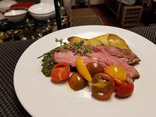 A beautifully plated roast beef accompanied by colorful roasted vegetables and herbs.