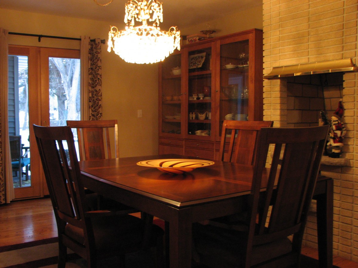 A cozy dining room with a wooden table, chairs, and a chandelier.