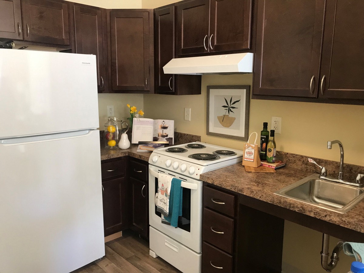 A cozy kitchen with dark cabinets and white appliances, including a fridge and stove.