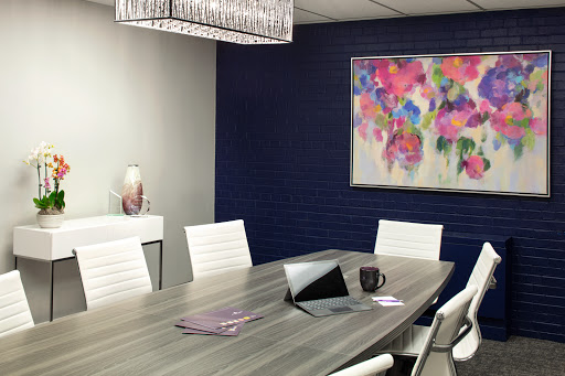 A stylish modern meeting room featuring a large conference table, white chairs, and vibrant artwork on the wall.