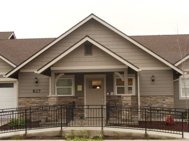 Front view of a suburban house with gray siding and stone accents.