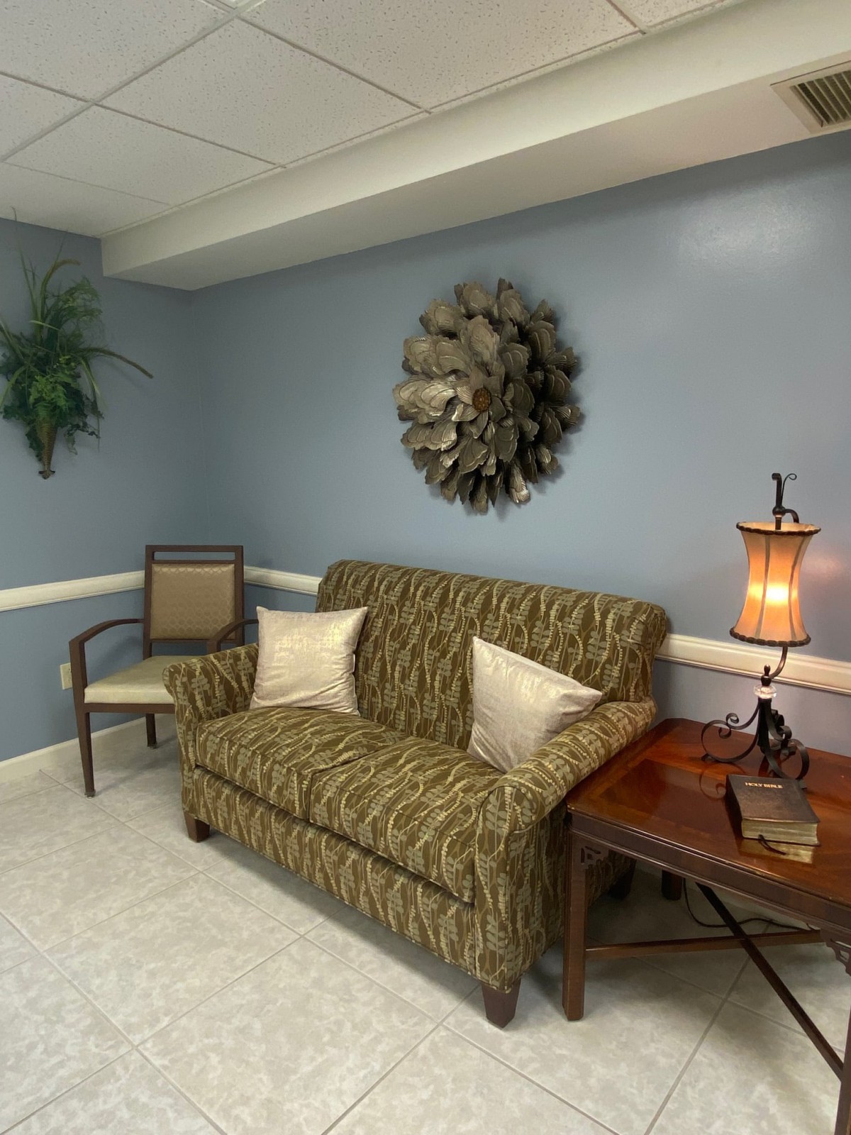 A cozy living room with a patterned sofa, decorative wall art, and a warm lamp.