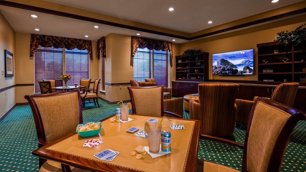 A comfortable lounge area with tables set for card games, surrounded by cozy chairs and a television.