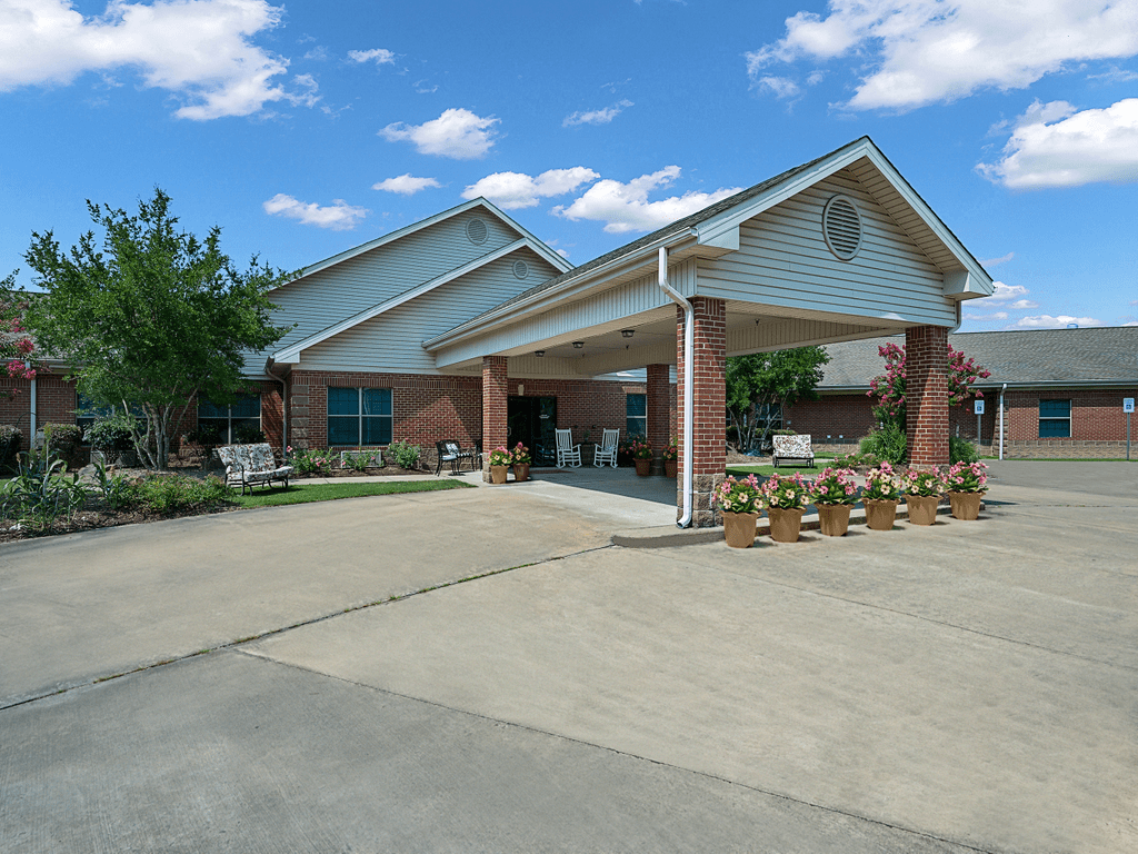 A suburban residential building with a covered entrance and landscaped surroundings.