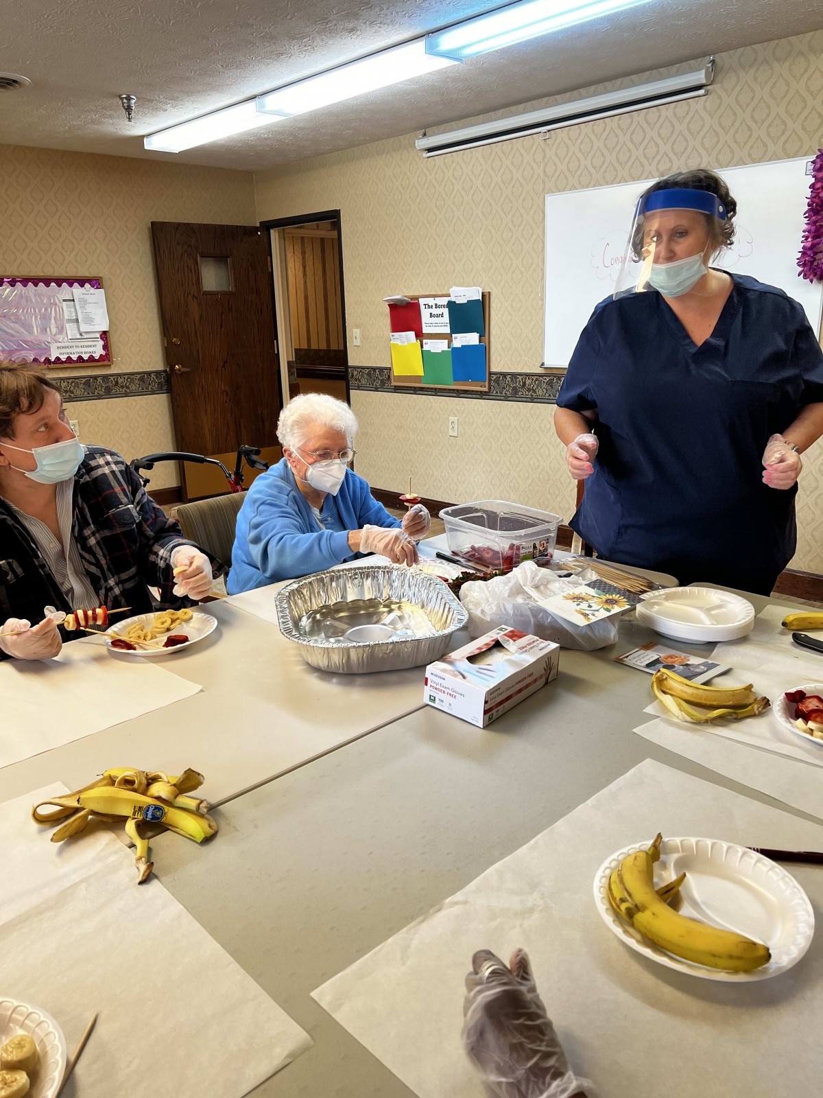 A group of elderly individuals engage in a crafting activity with the guidance of a healthcare worker.