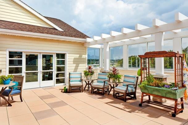 A sunny patio with comfortable seating and lush plants under a pergola.