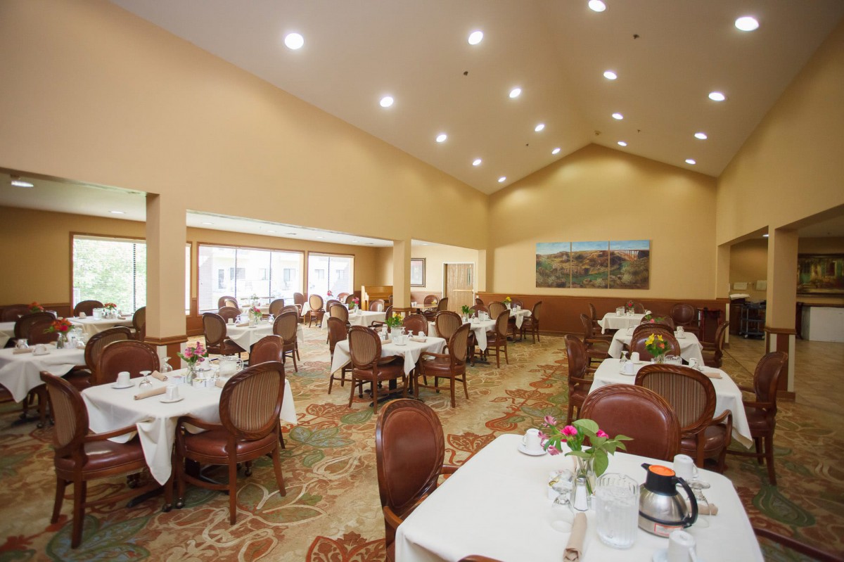 A spacious and elegantly decorated restaurant dining room with neatly arranged tables and chairs.