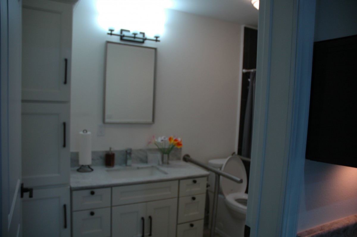 A modern bathroom with a vanity, mirror, and decorative flowers.