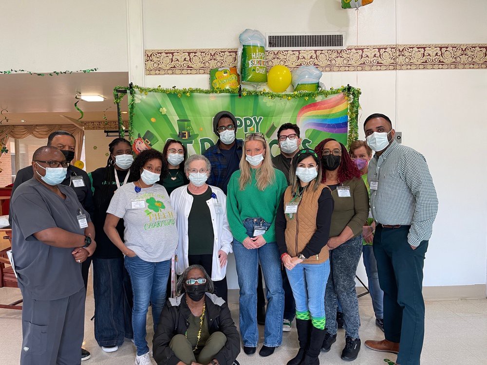 A group of people wearing masks posing together indoors in front of a colorful banner.