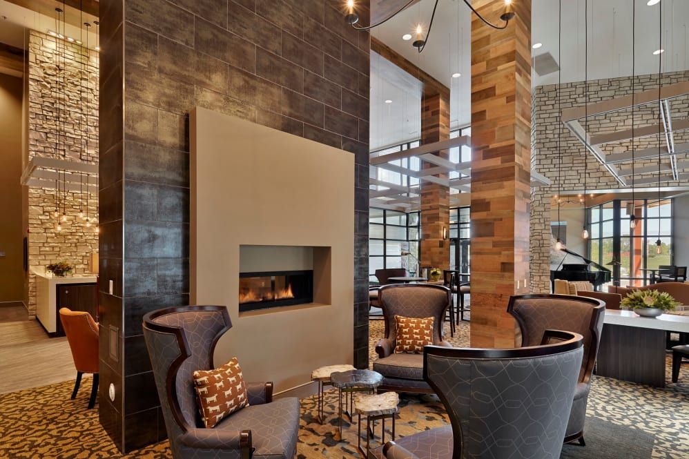 A modern lounge with a cozy seating area and fireplace, featuring elegant wood paneling.
