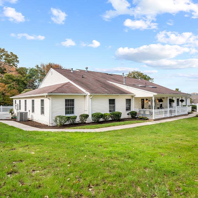 A single-story residential house with a well-maintained lawn under a partly cloudy sky.