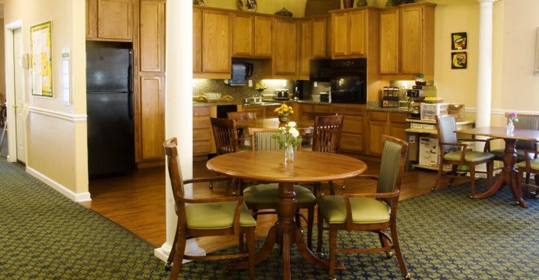 A cozy kitchen with wooden cabinets and a round dining table surrounded by chairs.
