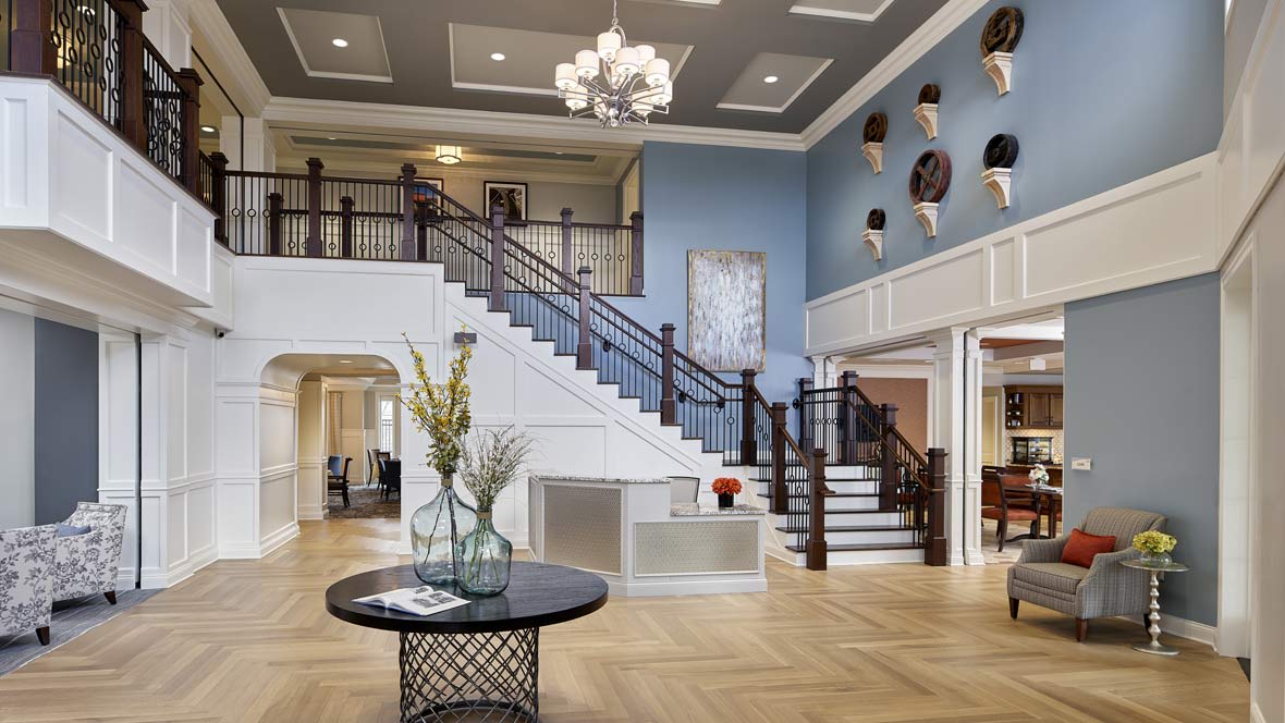 A modern lobby featuring a grand staircase, elegant chandelier, and stylish decor.